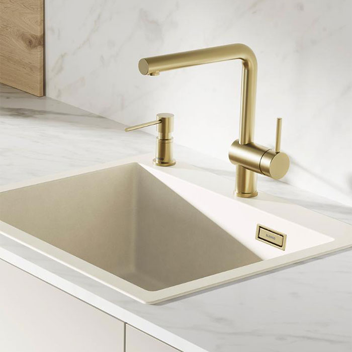 Lyst køkken med marmor og en køkkenvask i soft white med matchende køkkenarmatur i messing.